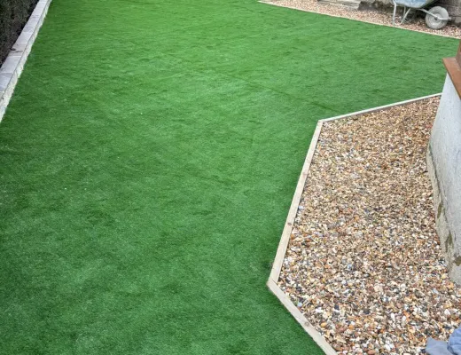 New artificial grass shaped around a pale gravel border in a walled garden