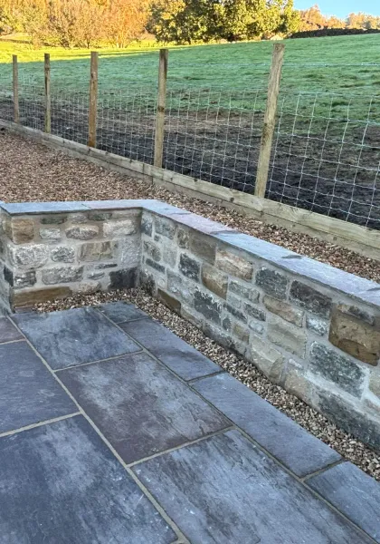 New natural stone retaining wall finished with dressed coping stones