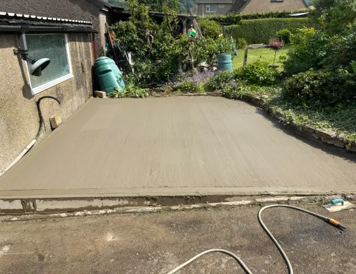 Fresh concrete path poured and levelled between garden borders