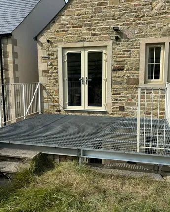 Galvanised steel platform with railings fabricated against a stone house