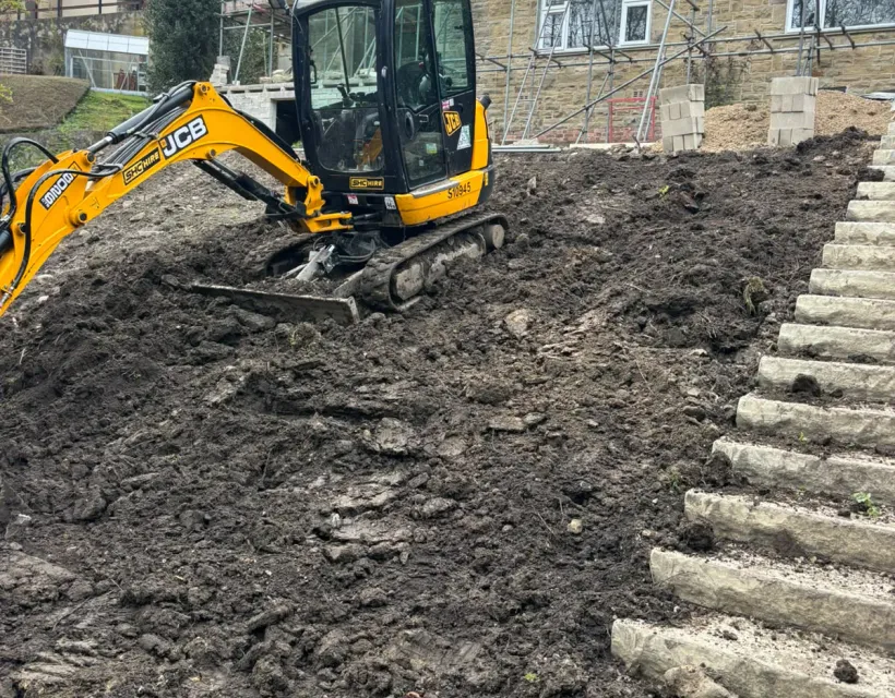 Excavated garden slope prepared with a mini digger for a new flight of stone steps