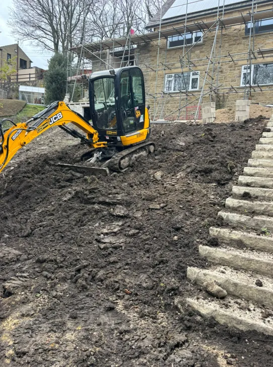 Excavated garden slope prepared with a mini digger for a flight of new stone steps