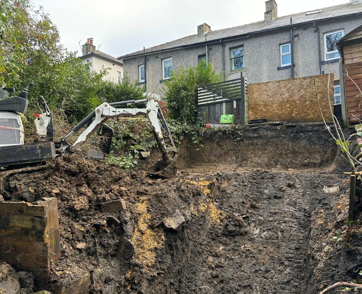Crown Hill Contracting mini digger excavating a back garden behind a row of terraced houses