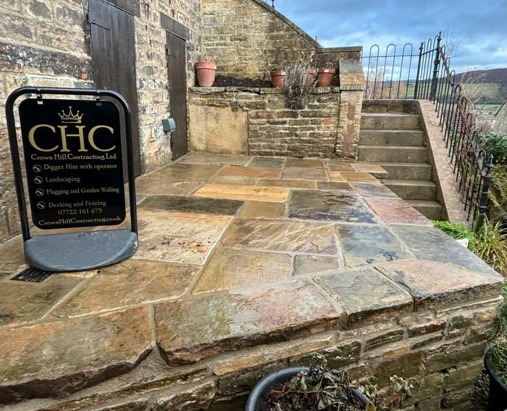 Crown Hill Contracting sign on a newly laid Yorkshire stone patio with raised stone walling