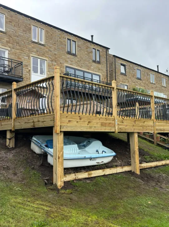 Large raised timber deck with decorative railings built into a steep riverside garden