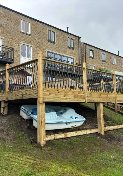 Raised timber deck with decorative metal railings built into a steep riverside garden