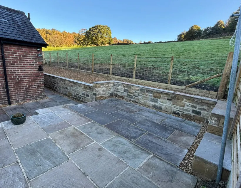 Finished slate patio with matching paths, gravel joints and a capped natural stone retaining wall