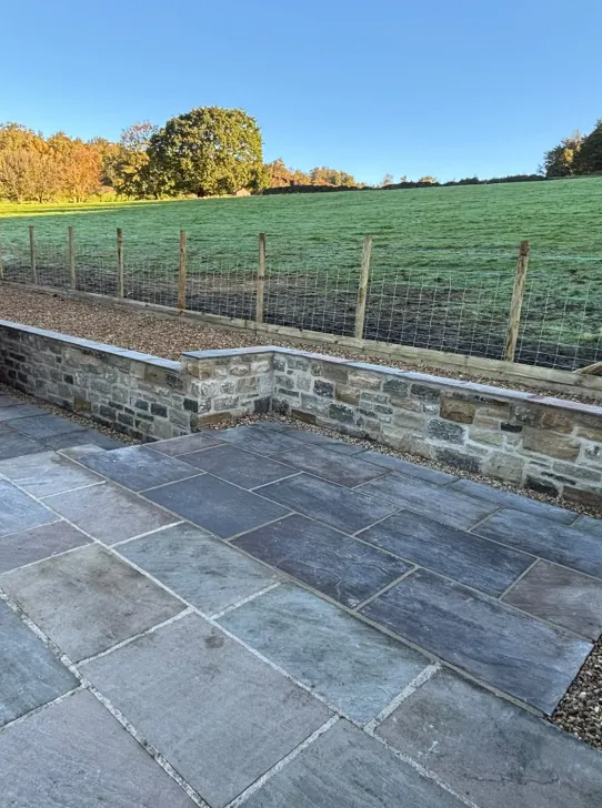 Finished slate patio with matching paths and a capped natural stone retaining wall