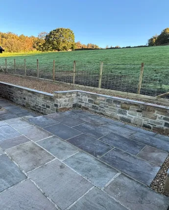 Finished slate patio with matching paths and a capped natural stone retaining wall